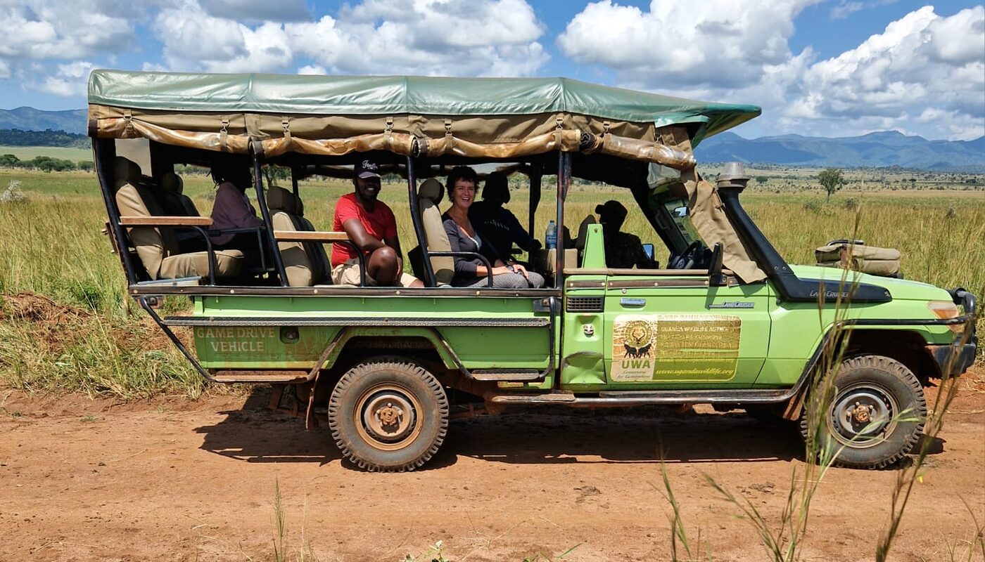 Travellers and their guide in the open-sided game drive vehicle on the plains