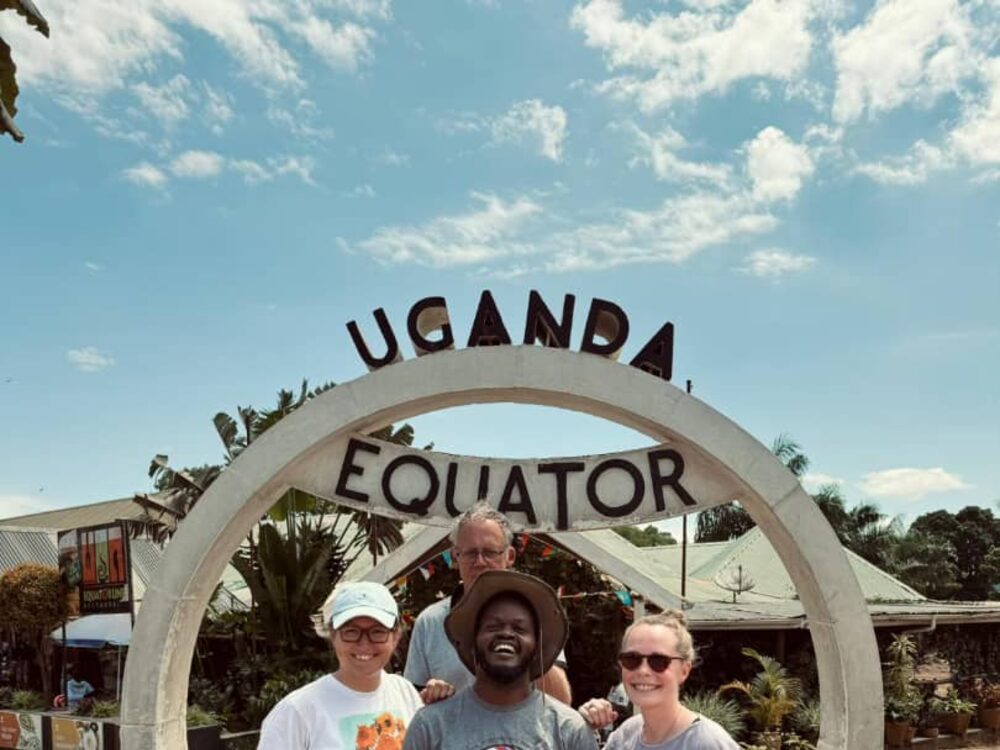 Travellers and their guide at the Uganda Equator monument